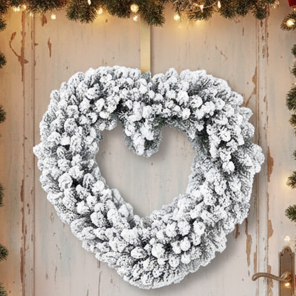 A heart-shaped wreath with green foliage and a snowy effect, designed for indoor use.