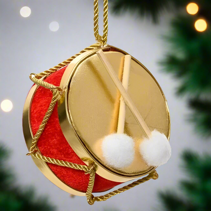 A hanging Christmas tree decoration featuring a red and gold colored drum with white furry drumsticks and a chain for hanging.