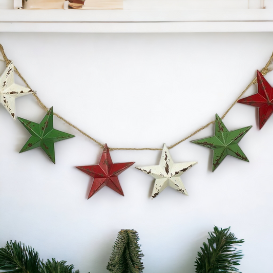 A rustic metal Christmas star garland in red, white, and green colors with a vintage style jute rope finish, displayed on a white wall.