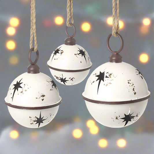 Set of three white Christmas bells with star cut-out designs, hanging from jute ropes.
