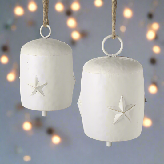 Set of 2 white cow bells with a star design, hanging from jute ropes.