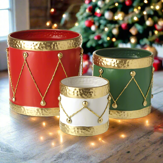 Set of three metal containers with Christmas drum design, in red, green, and white, with golden rope handles.