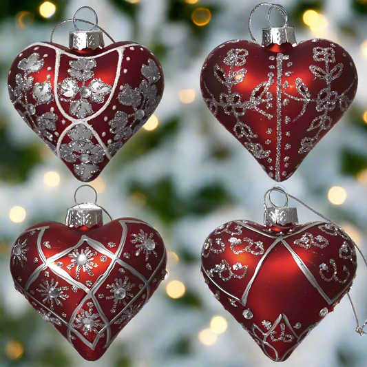 A set of four red and silver heart-shaped Christmas tree baubles with intricate ornamental designs and hanging strings.
