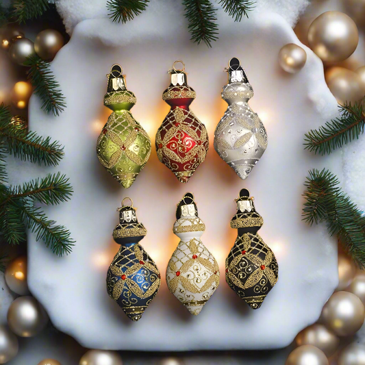 A set of six vintage-style glass Christmas ornaments in a variety of colors, including gold, green, red, white, and multicolored designs, displayed in a black frame.