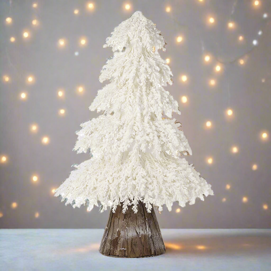 A white artificial Christmas tree with a rustic wooden base.