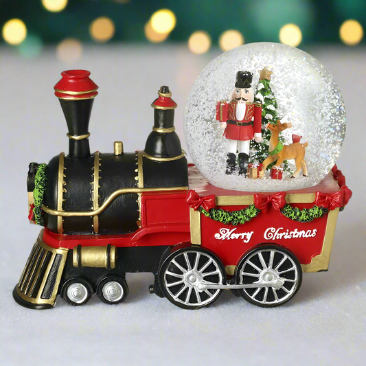 A resin snow globe featuring a train with a nutcracker scene inside. The train is black and red with festive decorations, and the snow globe is labeled 'Merry Christmas'.