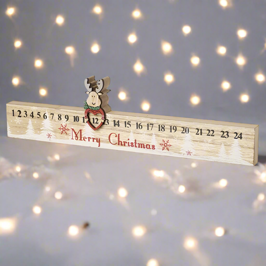 A wooden Advent calendar ruler with numbers from 1 to 24, featuring a reindeer at the top and the text 'Merry Christmas' printed on it.