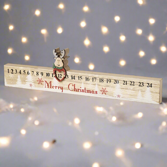 A wooden Advent calendar ruler with numbers from 1 to 24, featuring a reindeer at the top and the text 'Merry Christmas' printed on it.