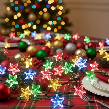 A string of multi-colored LED star lights placed on a wooden surface with a blurred Christmas tree and decorations in the background.