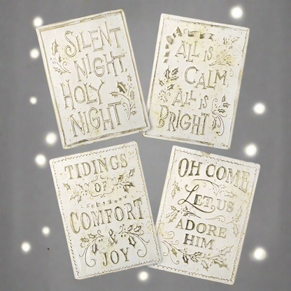 A set of four cream and gold aged effect Christmas signs with different texts, including 'Silent Night', 'All is Calm', 'Tidings of Comfort', and 'Oh Come Let us Adore Him'.