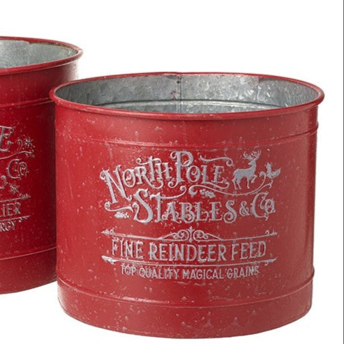A red metal bucket with 'North Pole Stables & Co Fine Reindeer Feed' text and a reindeer silhouette in white.