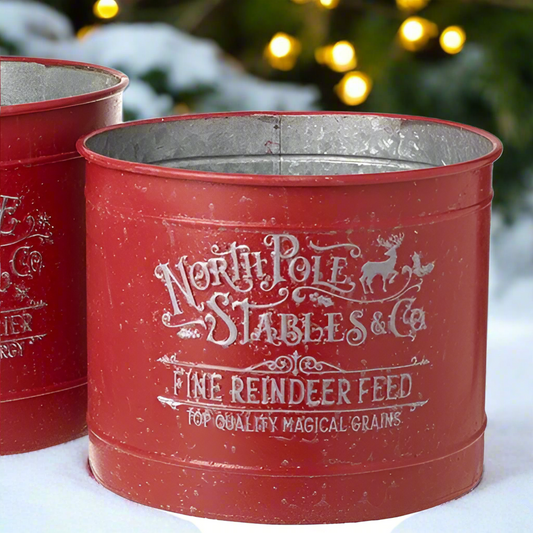 Red metal feed container with 'North Pole Stables & Co' text on a snowy background