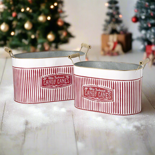 Two red and white striped metal buckets with 'CANDY CANES' text on them, designed for holiday decoration.