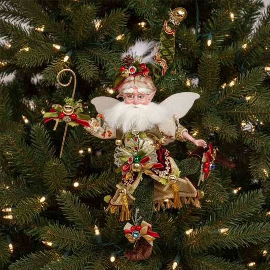 A decorative figure of a Santa fairy with green hat and coat, white beard and red shoes, holding a wand and bell, against a white background.
