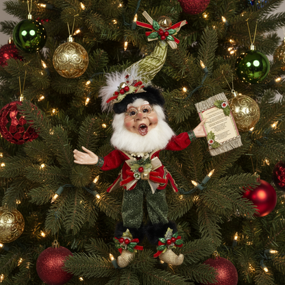 A vintage-style Christmas decoration featuring an elf with a green hat and coat, holding a scroll, and adorned with jewels and bells.