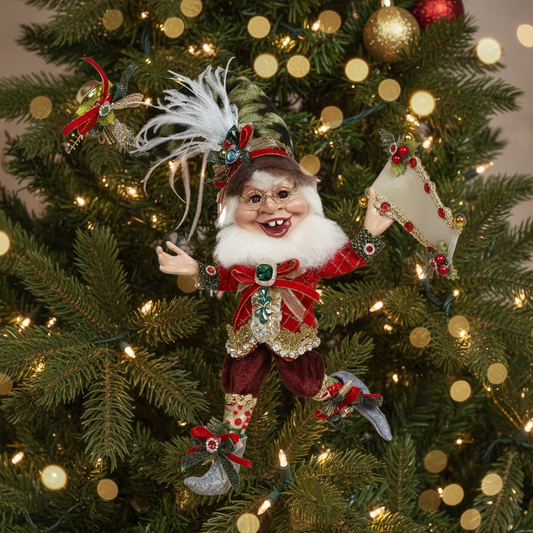 A decorative figurine of an elf with a mischievous expression, wearing a red outfit with Christmas-themed decorations, holding a banner and a set of balls.