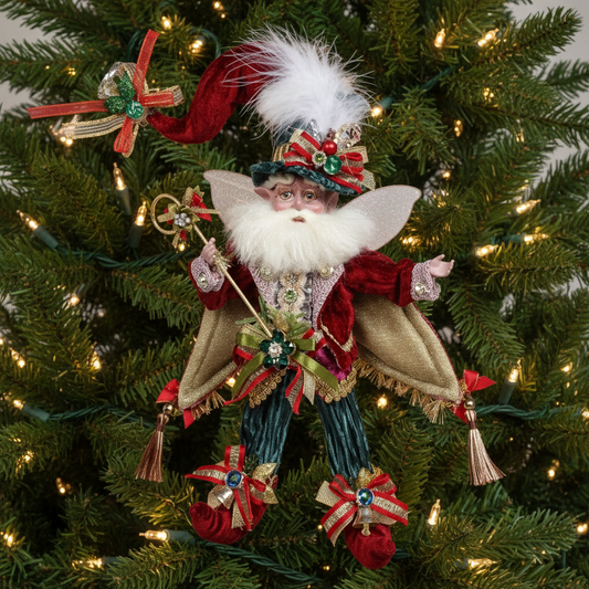A decorative figure of Santa Claus with a fairy-tale theme, adorned with a red jacket, green hat, white beard, and holding a wand and a sack. The figure is also decorated with jewels and bells.