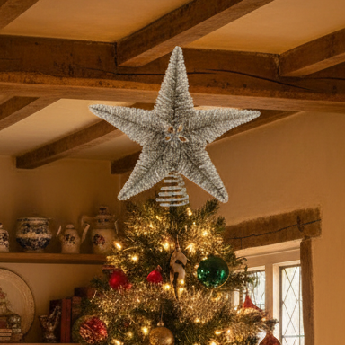 Decorated Christmas tree with a large star ornament in a room with wooden beams.