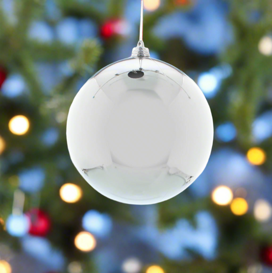 silver Christmas ball ornament hanging on a tree with blurred lights in the background