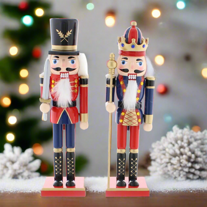Two traditional Christmas nutcrackers decorations, one with a top hat and the other with a crown, in blue and red uniforms, holding swords and staffs, standing on red bases.