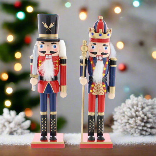Two traditional Christmas nutcrackers decorations, one with a top hat and the other with a crown, in blue and red uniforms, holding swords and staffs, standing on red bases.