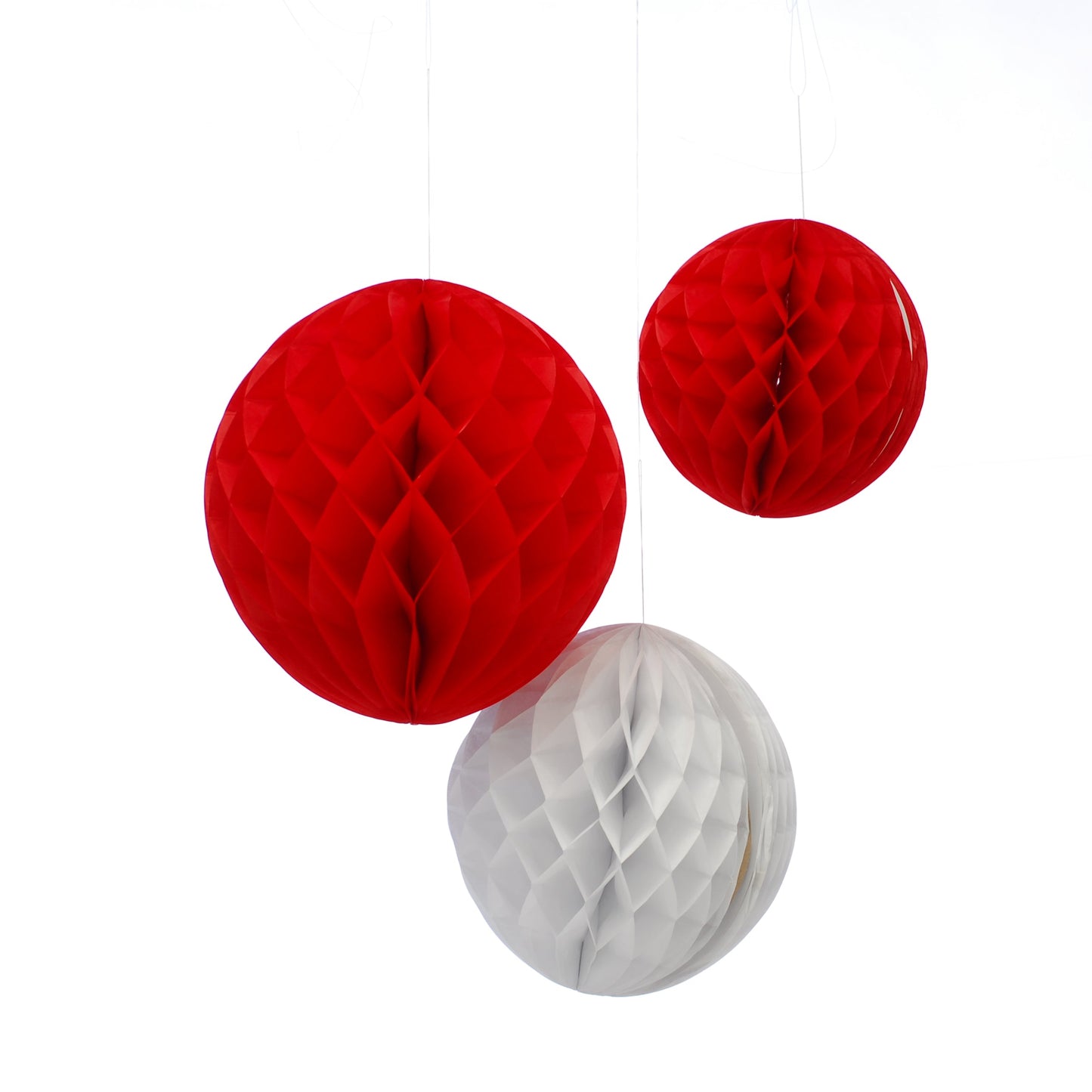 Three red and white honeycomb balls hanging against a white background