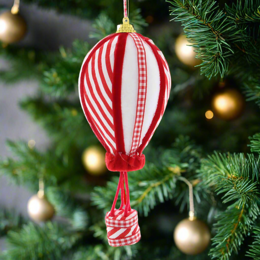 A red and white striped hot air balloon Christmas tree decoration with a gold hanging wire.