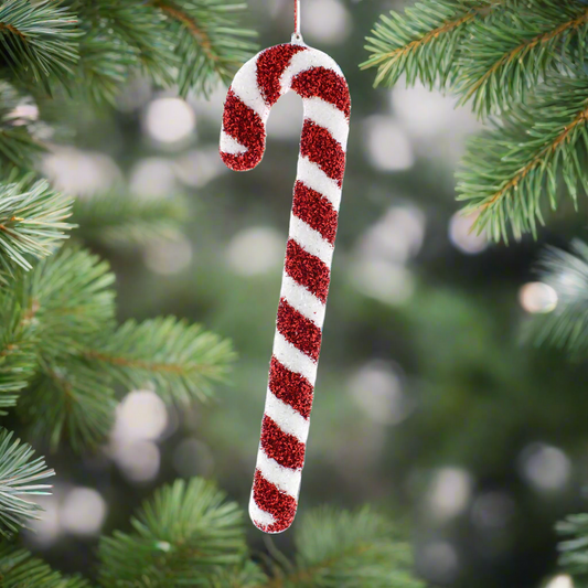 A red and white candy cane Christmas decoration hanging from a string against a white background.