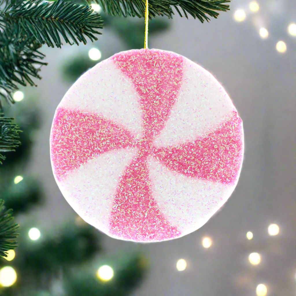 A pink and white candy stripe disc Christmas decoration with a silver hanging wire.