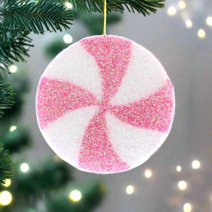 A pink and white candy stripe disc Christmas decoration with a silver hanging wire.