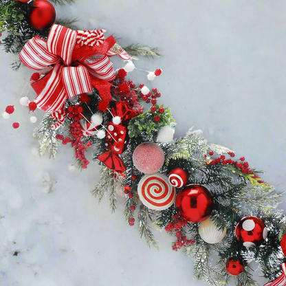 candy cane Christmas garland with baubles bows and berries in green foliage.