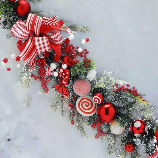 candy cane Christmas garland with baubles bows and berries in green foliage.
