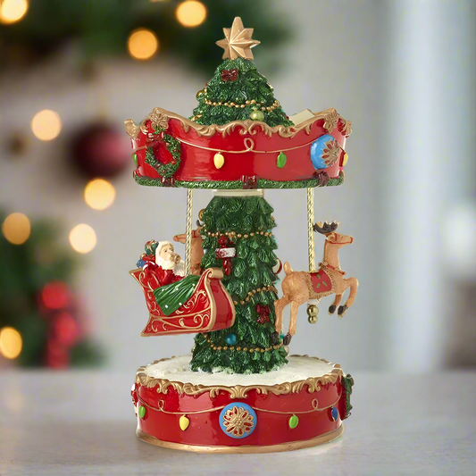 A decorative Santa Sleigh Spinning Christmas Merry Go Round with a Christmas tree, Santa Claus, and reindeer, placed on a red and gold ornately decorated base.