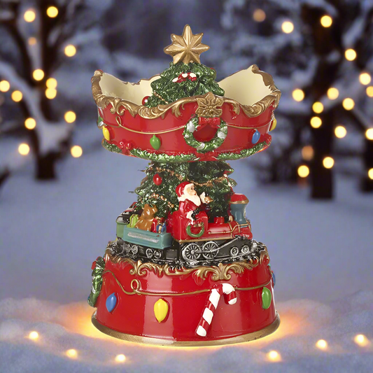 A decorative Christmas ornament featuring Santa Claus sitting on a train with a spinning base, decorated with a Christmas tree and festive elements.