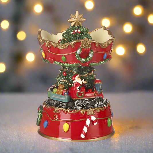 A decorative Christmas ornament featuring Santa Claus sitting on a train with a spinning base, decorated with a Christmas tree and festive elements.