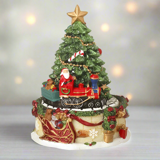 A musical Christmas tree ornament with a revolving base featuring Santa Claus and a train, surrounded by festive decorations.