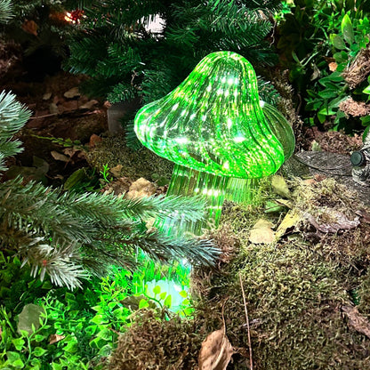 Green LED mushroom light on a forest floor with moss and leaves