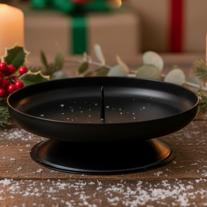 A black metal pillar candle holder with a spike in the center to keep the candle stable.