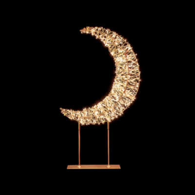 Decorative moon-shaped light on a stand against a black background