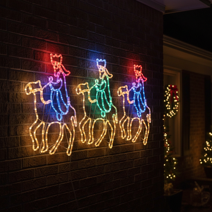 Colorful LED lights shaped like three kings on horses on a brick wall.