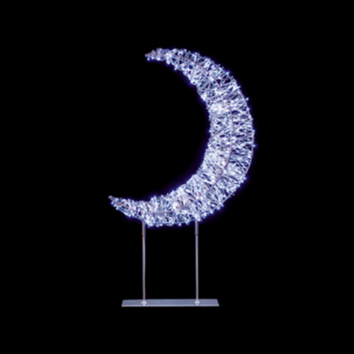 Decorative moon-shaped light on a stand against a black background