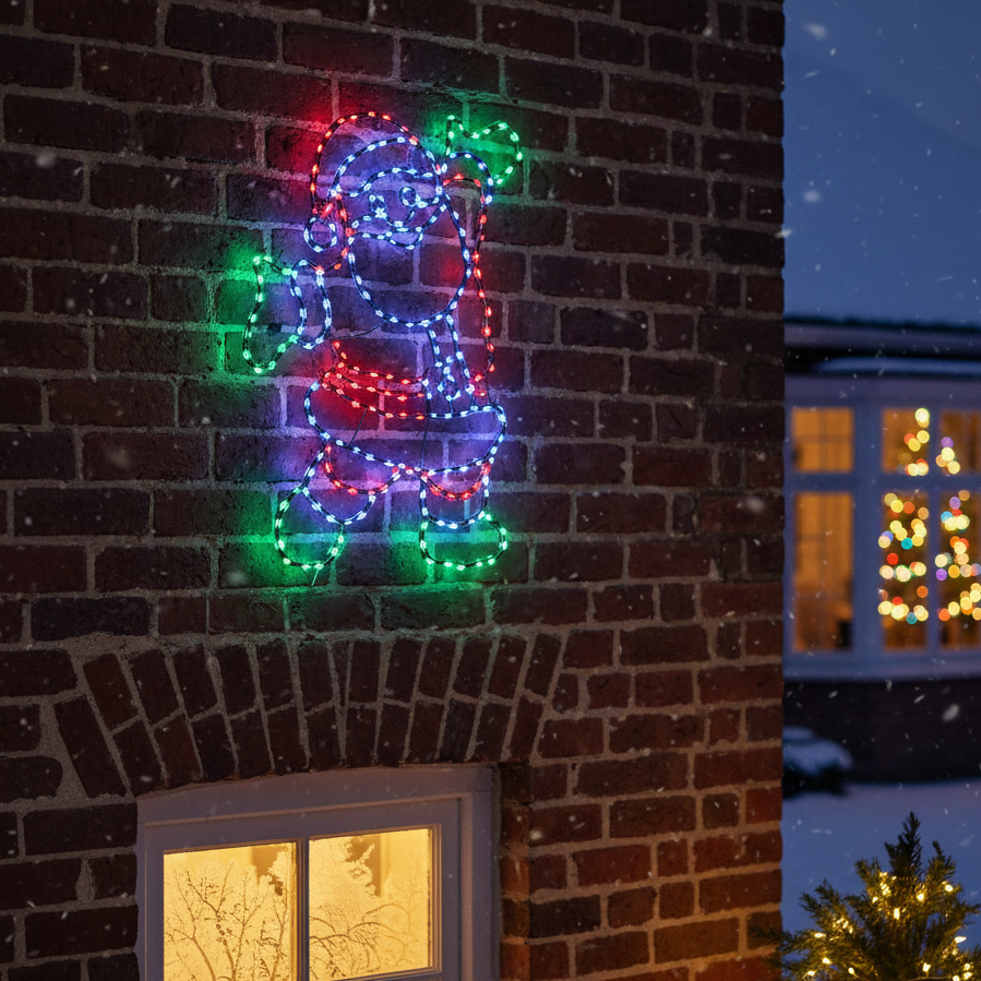 Colorful LED dog-shaped light decoration on a brick wall with a snowy night scene.