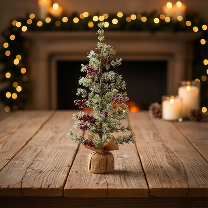 Small decorated Christmas tree on a wooden table with a fireplace and lights in the background