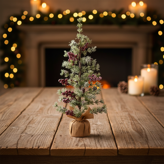 Small decorated Christmas tree on a wooden table with a fireplace and lights in the background